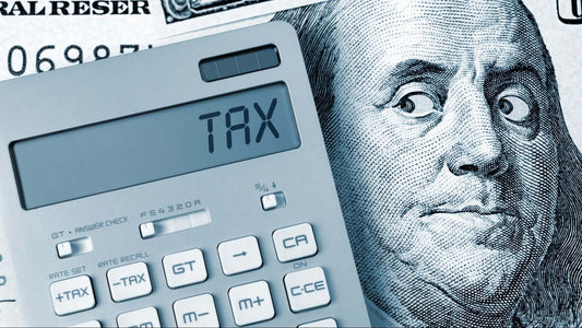 Calculator displaying 'TAX' next to a hundred dollar bill illustrating tax deductions.