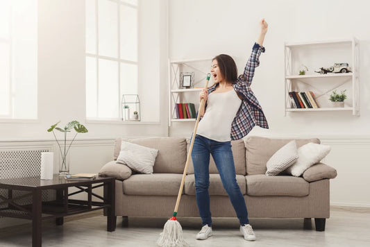 Woman joyfully cleaning her apartment with a mop, showcasing a fun and energetic cleaning atmosphere.
